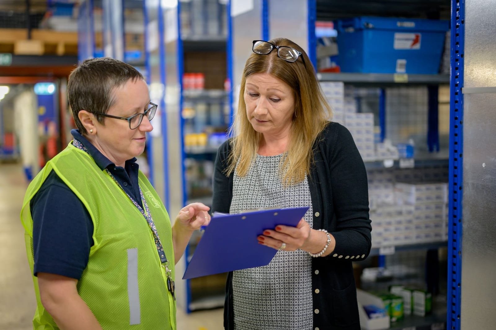 Two warehouse staff reviewing a shipment checklist on a clipboard, representing how importers evaluate and choose a freight forwarder in Pakistan